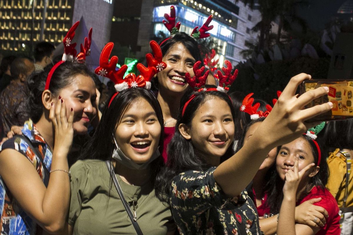 Warga mengambil swafoto saat menonton Christmas Carol di depan Grand Hyatt, Gondangdia, Menteng, Jakarta Pusat, Kamis, (19/12/2019). Tak hanya di bundaran HI, event ini juga digelar sejumlah spot ruang publik di sepanjang MH Thamrin - Sudirman.