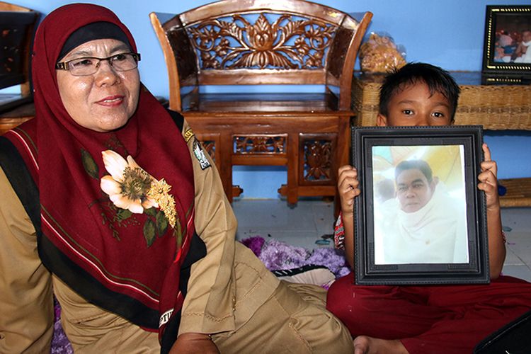 Marwani dan anak sedang memegang foto alm ayahnya yang meninggal di Arab Saudi saat melaksanakan ibadah haji pada tahun 2013 lalu, di rumahnya di Kecamatan Kawai XVI, Aceh Barat, Minggu (03/09/17)