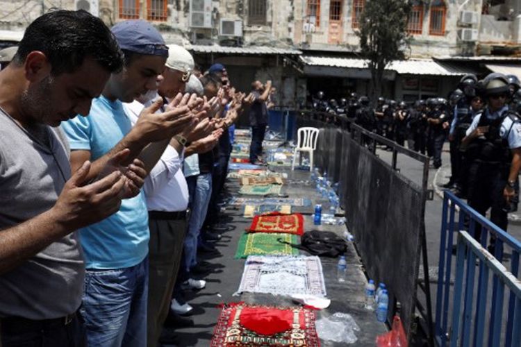 Warga Palestina menjalani ibadah Shalat Jumat di luar pintu masuk menuju kawasan Kota Tua Yerusalem di depan Masjid Al-Aqsa, Jumat (21/7/2017).  Israel melarang pria Palestina yang berusia di bawah 50 tahun untuk masuk ke kawasan Kota Tua dan menjalani Shalat Jumat, menyusul insiden penembakan dua polisi Israel.