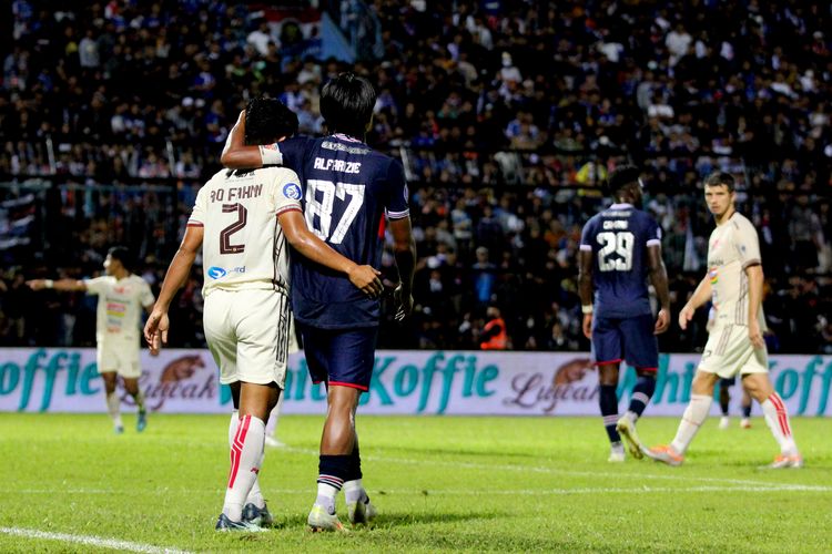 Pemain Arema FC Johan Ahmad Farizi dan pemain Persija Jakarta saling berpelukan usai duel berebut bola saat pertandingan pekan ke-7 Liga 1 2022-2023 yang berakhir dengan skor 0-1 di Stadion Kanjuruhan Kepanjen, Kabupaten Malang, Minggu (28/8/2022) malam.