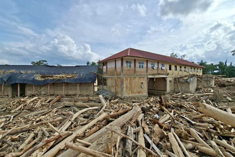 Kayu pohon berukuran besar yang terbawa arus banjir tersangkut di atap bangunan Pondok Pesantren Darul Mukhlisin Aceh Tamiang, Jumat (13/12/2025).