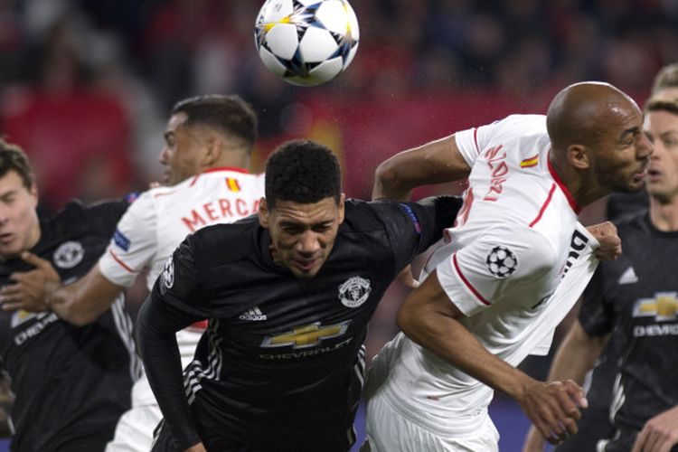 Aksi bek Manchester United, Chris Smalling (tengah), saat berduel dengan gelandang Sevilla, Steven NZonzi (kedua dari kanan), dalam laga leg 1 babak 16 besar Liga Champions 2017-2018 di Stadion Ramon Sanchez Pizjuan, Sevilla, Spanyol, pada Rabu (21/2/2018).