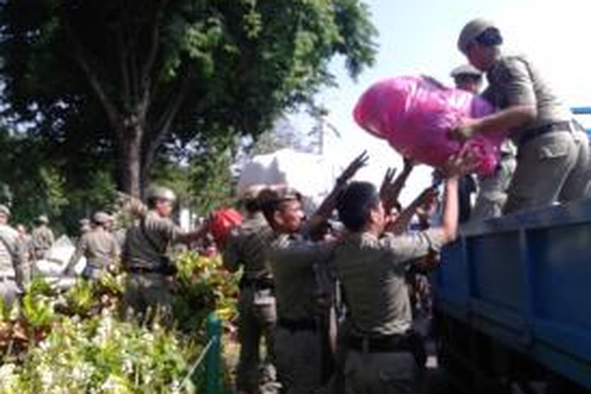 Petugas Satpol PP mengangkat barang PKL dari semak tanaman dan pot di Monas. Sabtu (2/8/2014).