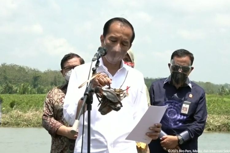 Presiden Joko Widodo menunjukkan kepiting yang ditangkap usai melakukan penanaman mangrove di Kecamatan Cilacap Utara, Kabupaten Cilacap, Jawa Tengah, Kamis (23/9/2021).