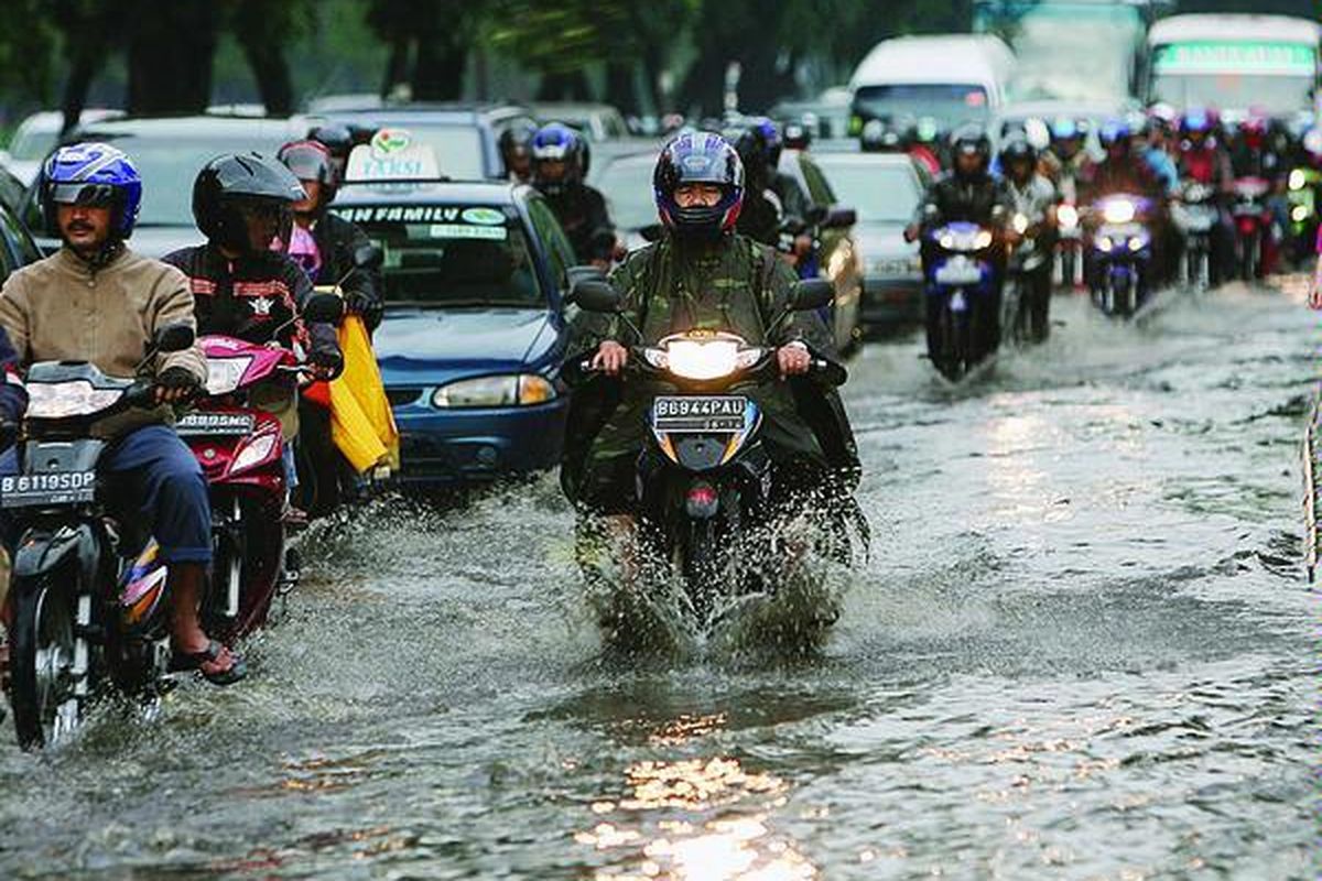 Ilustrasi: Penggguna jalan melintasi genangan air setelah hujan deras.