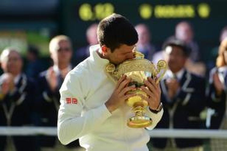 Petenis Serbia, Novak Djokovic, mencium trofi juara Wimbledon yang dia dapatkan setelah mengalahkan petenis Swiss, Roger Federer, pada partai final yang berlangsung di All England Tennis Club, London, Minggu (6/7/2014). Djokovic menang 6-7 (7), 6-4, 7-6 (4), 5-7, 6-4.