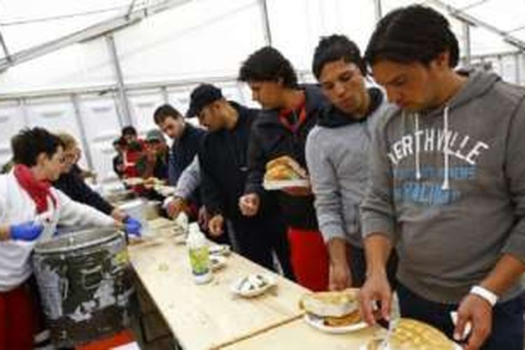 Para migran mengambil makanan di tempat penampungan di gedung olahraga Hanau, Jerman