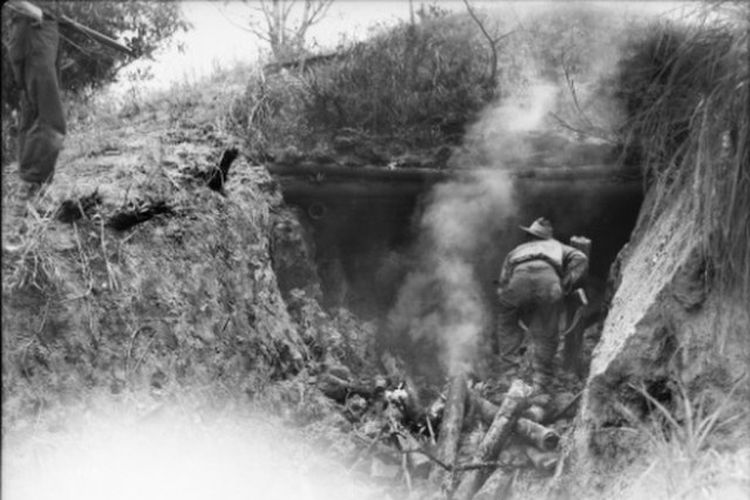 Prajurit J.A. Gresham, Kompi Markas, Batalyon Infanteri ke-2/24, memeriksa sebuah kotak obat Jepang yang hancur akibat tembaka peluru angkatan laut dan penyembur api pada 4 Mei 1945