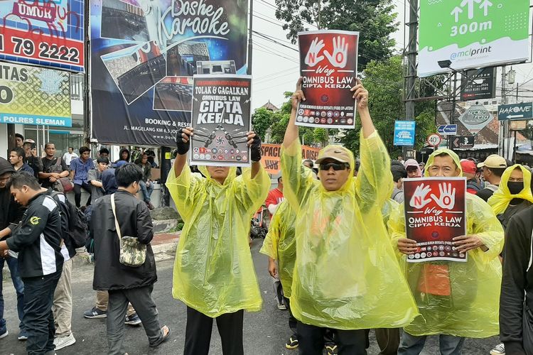 Beberapa orang yang turut aksi di Simpang Tiga Gejayan mengenakan mantel saat hujan turun.