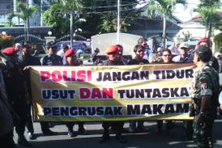Puluhan masyarakat membentangkan spanduk di depan mapolresta kota yogyakarta, desak polisi segera tangkap pelaku pengerusakan makam
