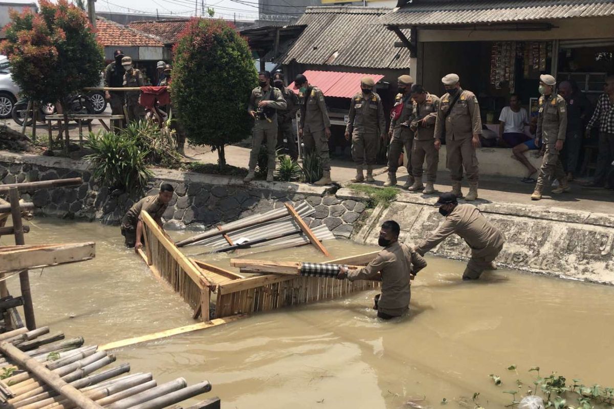 Satuan Polisi Pamong Praja (Satpol PP) Kabupaten Bekasi menertibkan bangunan dan lapak liar di sepanjang jalan wilayah Gandaria - Poponcol, Desa Cibarusah Kota yang berdiri di atas tanah irigasi, Sabtu (17/09/22).