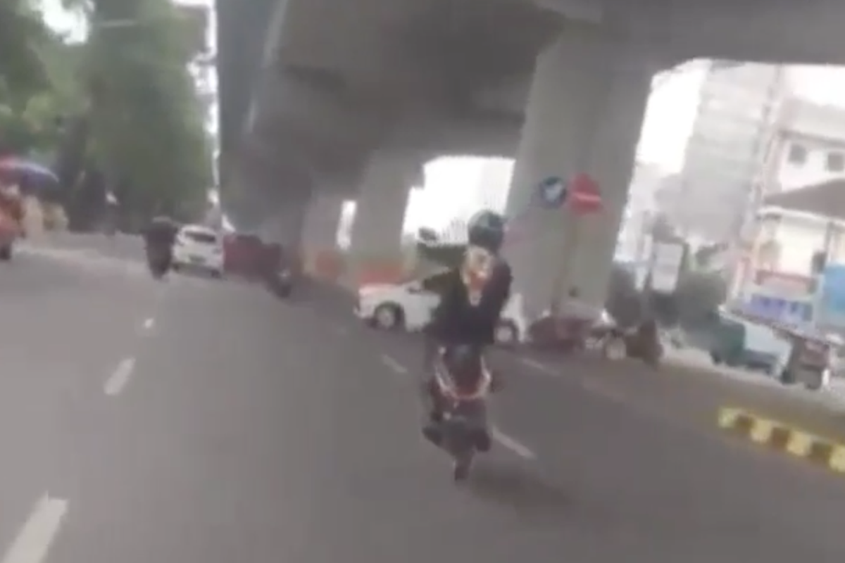 Pengendara motor wheelie di jalan raya