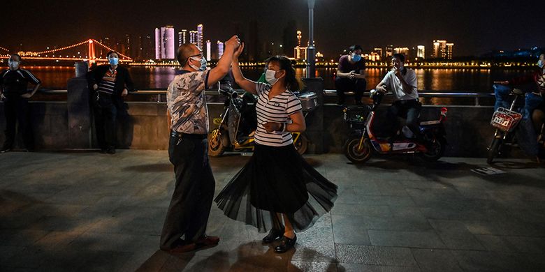 Sejumlah pasangan dengan mengenakan masker menari di sebuah taman di sebelah Sungai Yangtze, Wuhan, Provinsi Hubei, China, Selasa (12/5/2020). Memasuki enam pekan bebas dari lockdown yang diterapkan akibat pandemi Covid-19 sejak Januari lalu, warga Wuhan kembali beraktivitas walau dalam kondisi terbatas.