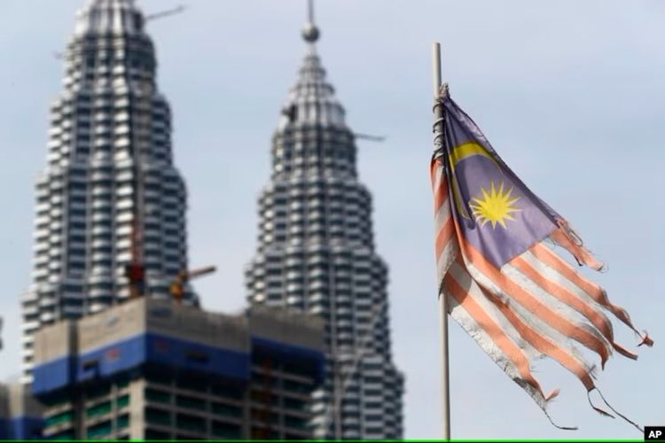 Bendera nasional Malaysia yang tampak lusuh berkibar di depan Menara Petronas di Kuala Lumpur, Malaysia.