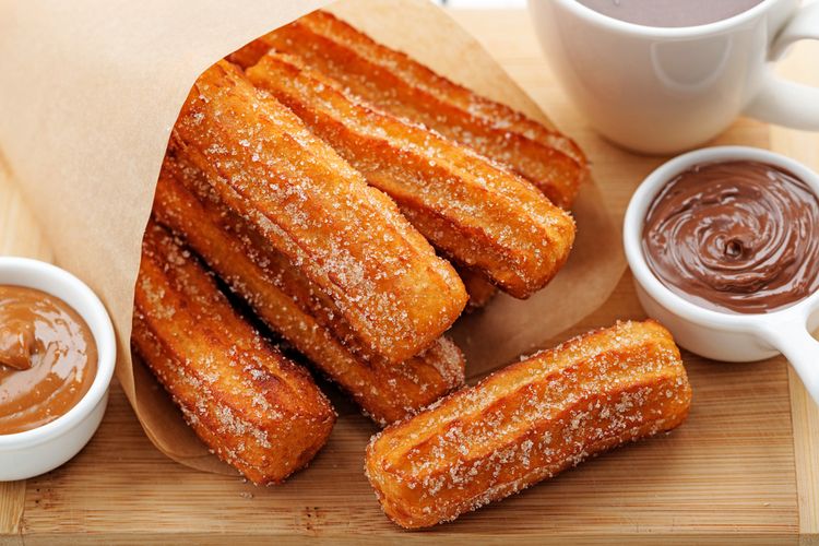 Ilustrasi churro bertabur gula pasir dan saus cokelat. 