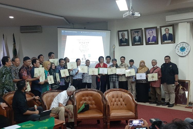 Para alumni Fakultas Kehutanan UGM angkatan 1980 saat berfoto sembari menunjukan ijazah asli mereka. para teman angkatan Presiden Joko Widodo ini berfoto di depan layar besar yang menampilkan foto ijazah S1 Presiden Joko Widodo.