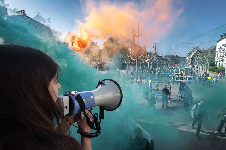 Demonstran berbicara melalui pengeras suara di tengah asap warna-warni yang membumbung saat aksi memperingati Hari Buruh Internasional 2019 di Strasbourg, Perancis, Rabu (1/5/2019). Aksi yang diperingati tahunan setiap tanggal 1 Mei itu digelar serentak di seluruh dunia untuk menyuarakan kesejahteraan bagi buruh.