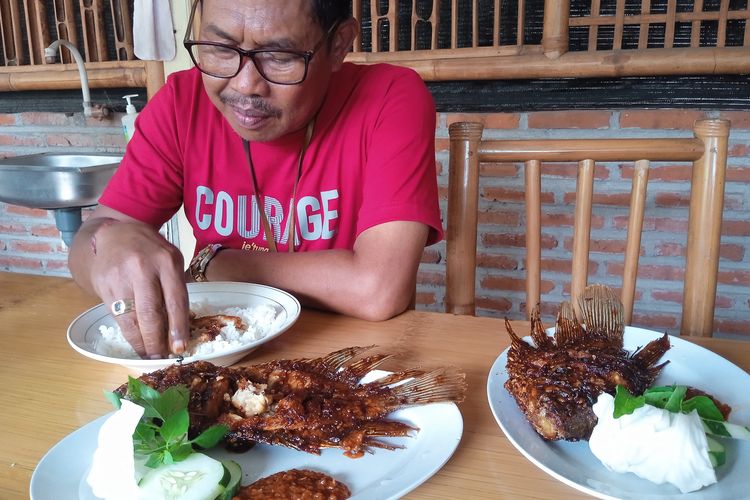 Salah satu pengunjung Lesehan Mewah Nganjuk, Suwandi (57), saat menyantap Gurami Bakar Pedas, Senin (13/1/2025).