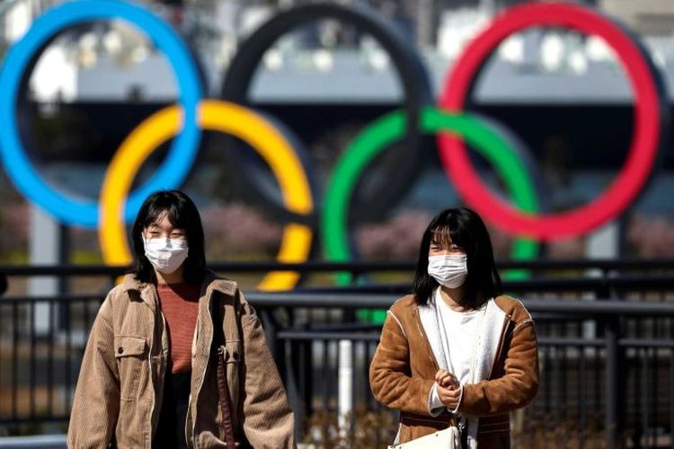 Dua warga berjalan di depan simbol Olimpiade di Tokyo, Jepang.