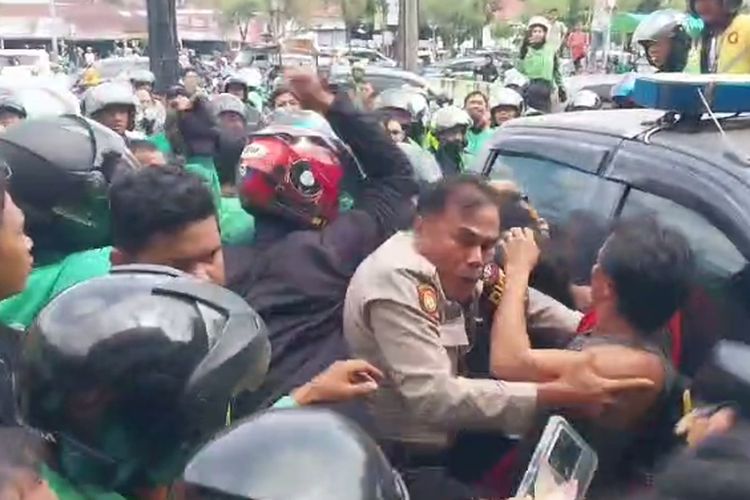 Petugas kepolisian saat berupaya membawa tiga pelaku pengeroyokan dari kerumunan massa ojol, di Jalan HR Soebrantas, Kelurahan Tobek Godang, Kecamatan Bina Widya, Pekanbaru, Riau, Kamis (23/5/2024).