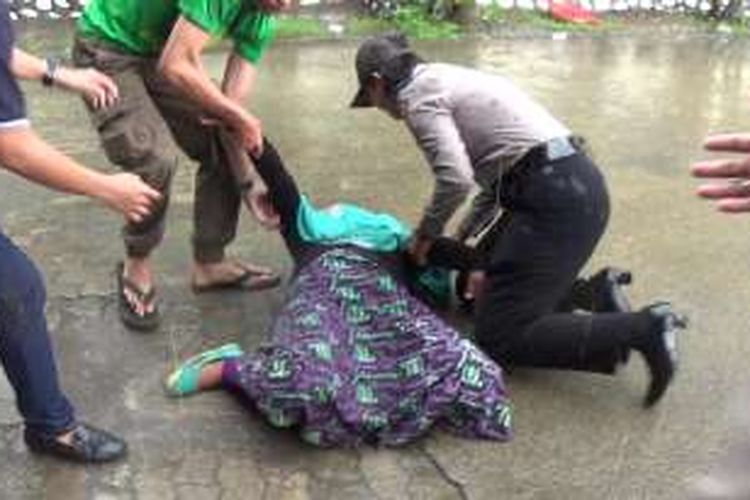 Salah seorang keluarga korban pembunuhan terjatuh pingsan ditengah hujan deras saat berupaya menyerang terdakwa di Pengadilan Negeri Takalar, Kabupaten Takalar, Sulawesi Selatan. Rabu, (16/11/2016).