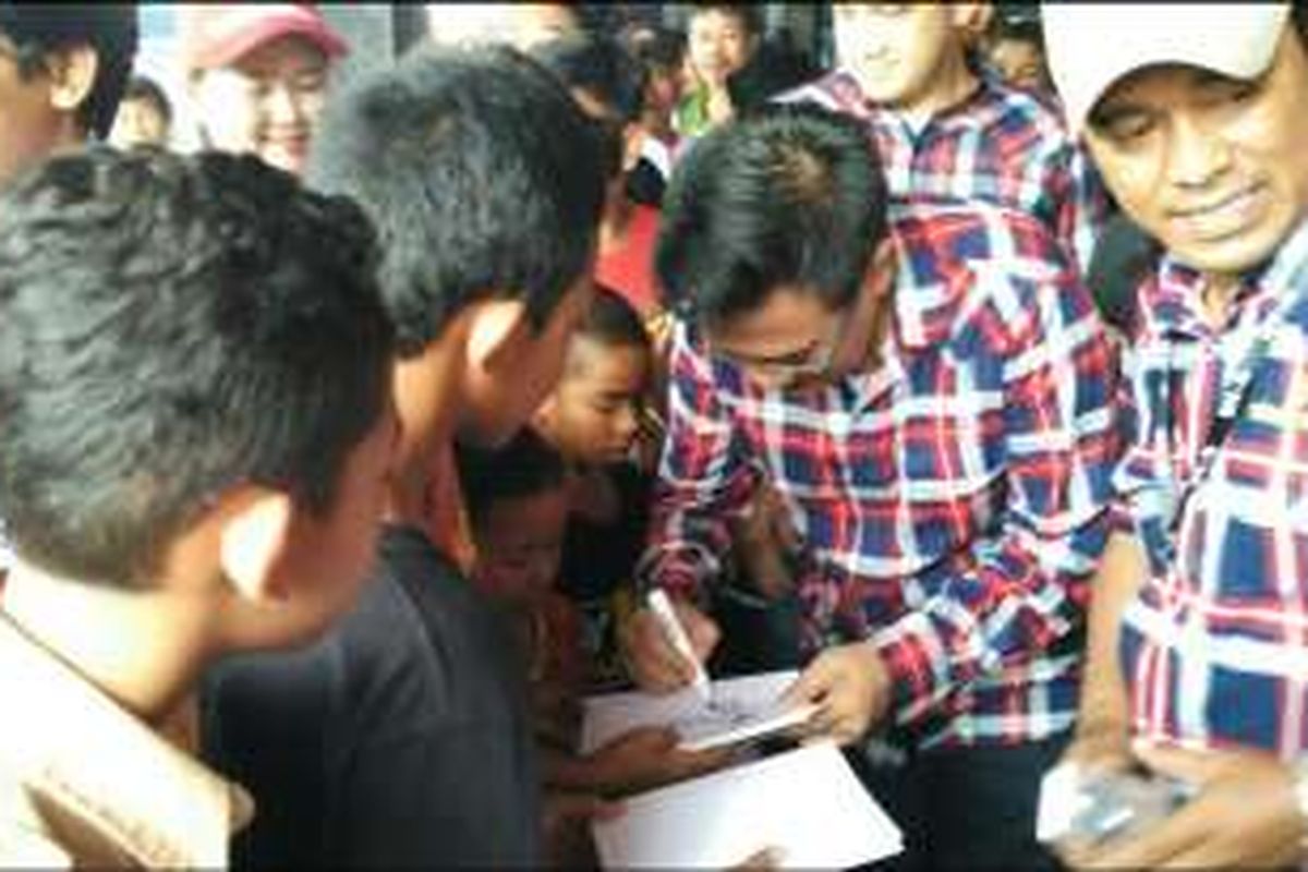 Calon wakil gubernur DKI Jakarta Djarot Saiful Hidayat menandatangani buku anak-anak saat blusukan di Kompleks Kopti, Kelurahan Semanan, Kalideres, Jakarta Barat, Rabu (30/11/2016). 