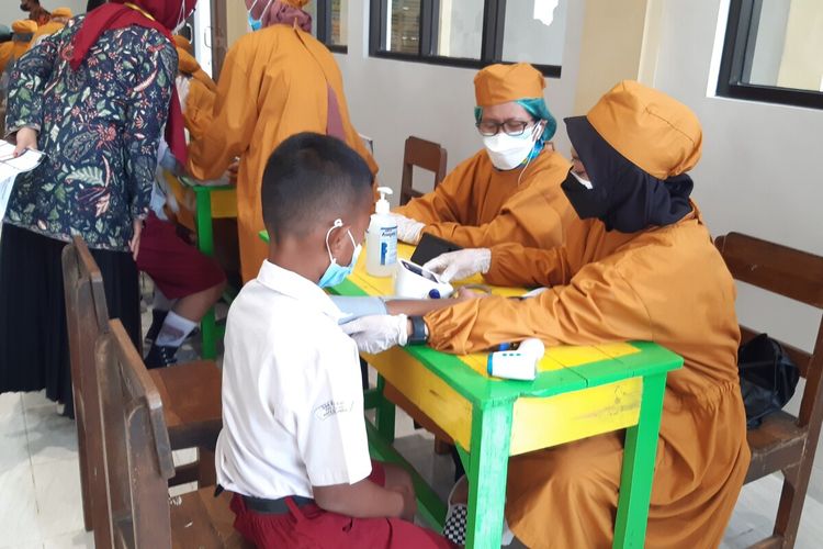 Petugas kesehatan melakukan pemeriksaan terhadap anak dalam vaksinasi Covid-19 anak usia 6-11 tahun di SDN Kleco I dan II Solo, Jawa Tengah, Selasa (21/12/2021).