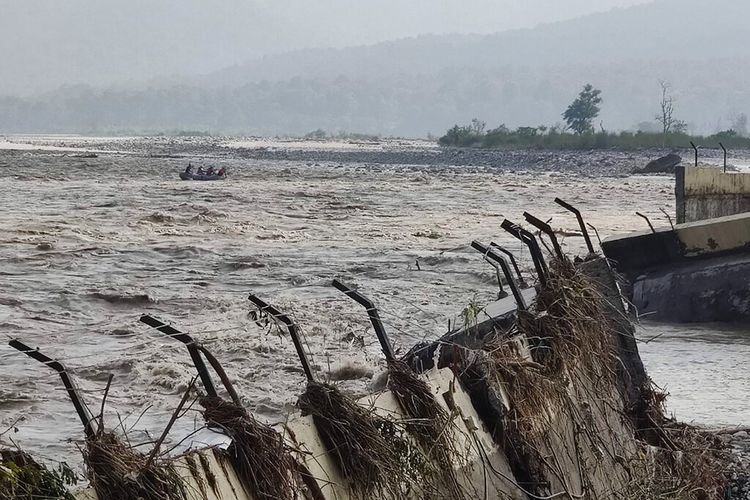 Tim penyelamat mengirimkan jatah dan pasokan penting ke desa Chukum di seberang sungai Kosi yang banjir, dengan dinding penahan hotel Lemon Tree yang rusak terlihat di sebelah kanan, di negara bagian Uttarakhand, India, Rabu, 20 Oktober 2021.