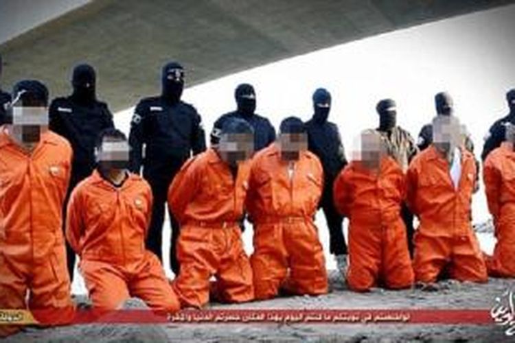 Anggota ISIS, yang berbaju hitam dan berdiri, dengan para tawanan mereka.