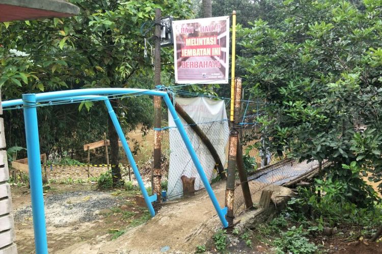 Spanduk peringatan hati-hati melintasi jembatan gantung Indiana Jones di RT 012 RW 002 Kelurahan Srengseng Sawah, Jagakarsa, Jakarta Selatan, yang akan dibangun. Foto diambil Selasa (13/3/2018).