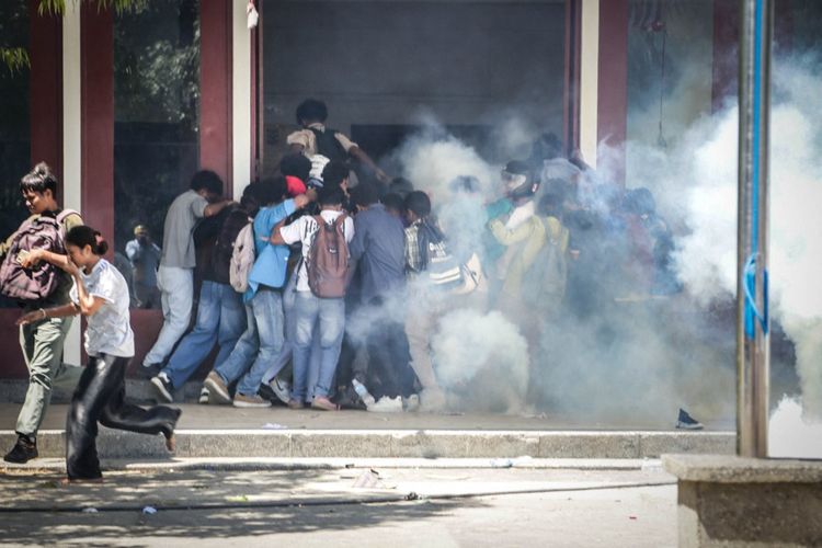 Mahasiswa dari sejumlah universitas di Universitas Nasional Timor Leste (UNTL) Dili pada 15 September 2025 berlarian dari gas air mata yang ditembakkan polisi selama protes mereka terhadap rencana pembelian 65 mobil bagi anggota parlemen.