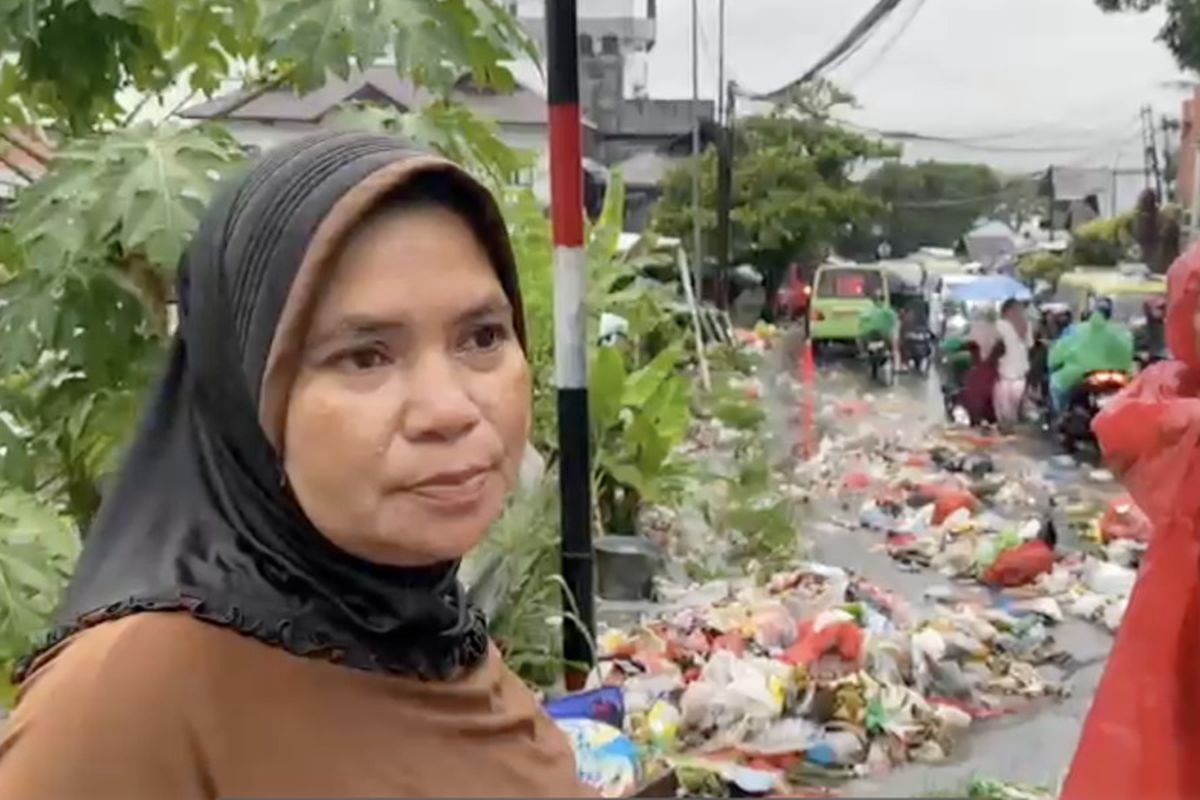 AKSI HAMBURKAN SAMPAH - Dua ibu-ibu warga Jalan Kebun Cengkeh, Kecamatan Sirimau, Kota Ambon, hamburkan sampah di jalan saat hujan deras. Senin (17/3/2025). Mereka kesal banyak warga yang buang sampah sembarangan hingga masuk ke rumah mereka yang berada persis di bawah jalan.