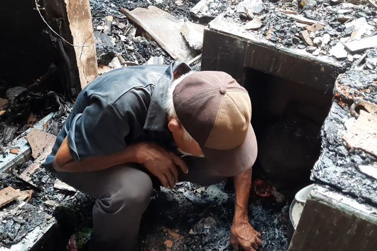 Seorang lansia bernama Suhanda (69) saat mengais barang-barang pribadinya usai rumahnya di kawasan Setiabudi. Jakarta Selatan, terbakar pada Jumat (21/7/2023).