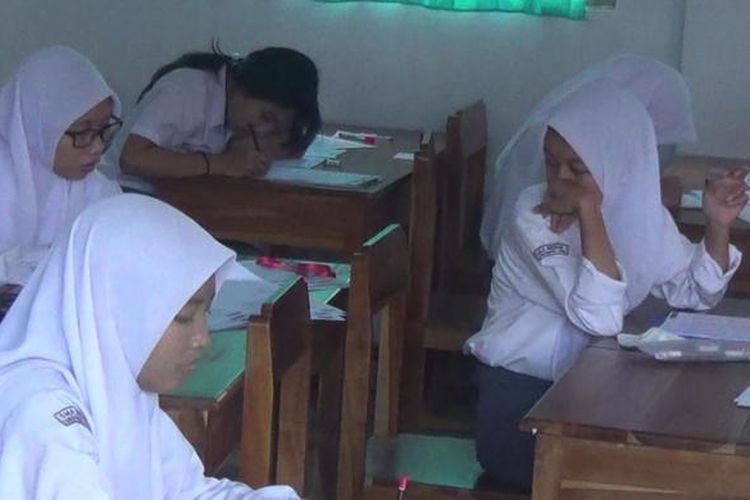 Salah seorang peserta Ujian Nasional (UN) di salah satu Sekolah Menengah Atas (SMA) Negeri di Sungguminasa, Kabupaten Gowa, Sulawesi Selatan mencontek dan bekerjasama dengan peserta UN lainnya. Senin, (04/04/2016).