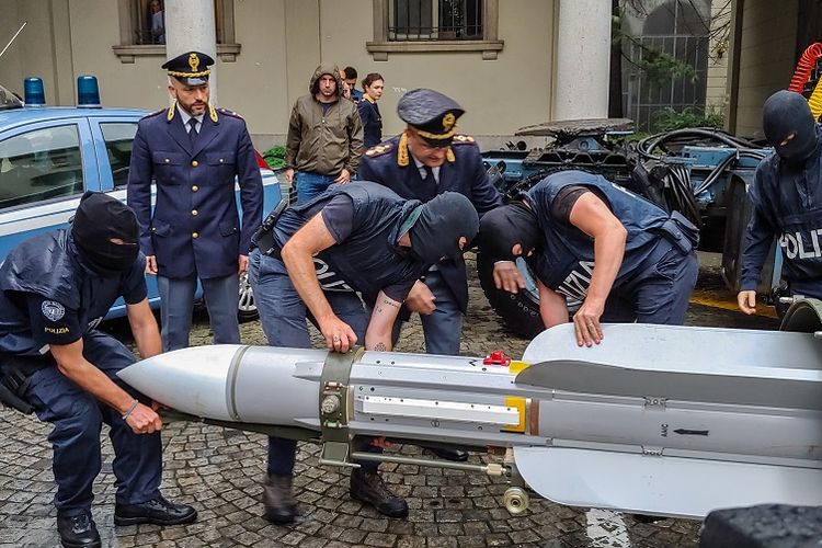 Foto yang dirilis kepolisian Italia, pada Senin (15/7/2019), menunjukkan petugas polisi yang membawa rudal Matra, sebagai bagian dari persenjataan yang disita dalam penggerebekan di Turin.