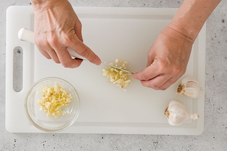 Mencincang bawang putih menggunakan pisau tajam sampai halus dan lembut.