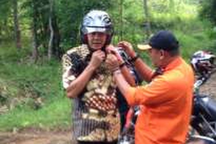 Gubernur Jateng Ganjar Pranowo dibantu petugas melepas helm seusai menaiki motor trail menerabas perbukitan untuk pembukaan jalur Banjarnegara-Kebumen, Kamis (19/2/2016) sore kemarin.