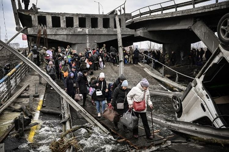 Orang-orang menyeberangi jembatan yang hancur saat mereka dievakuasi dari Kota Irpin, barat laut Kiev, selama penyerangan dan pengeboman besar-besaran pada Sabtu (5/3/2022) atau hari ke-10 invasi Rusia ke Ukraina. 