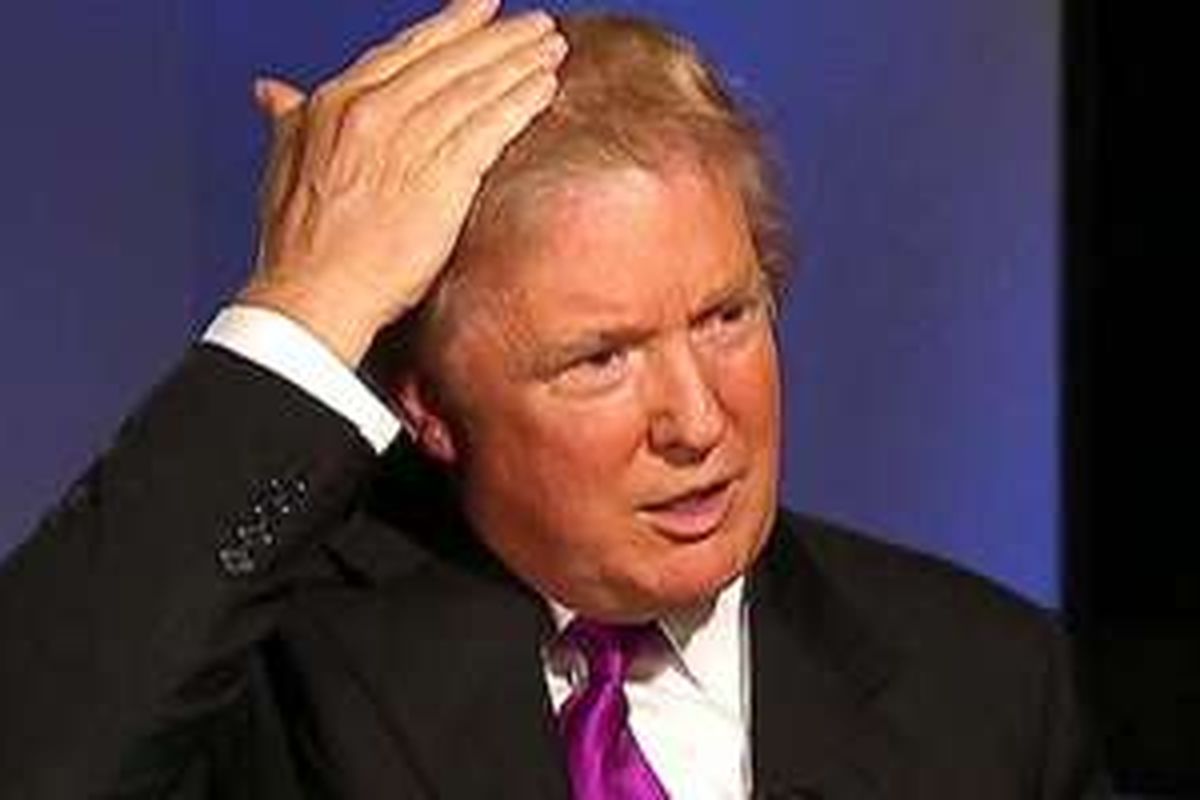 Donald Trump sedang merapikan rambut bagian depan saat sedang berkampanye. 