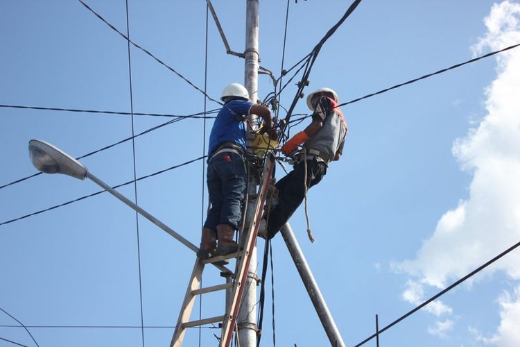 Karyawan PT PLN sedang memperbaiki jaringan listrik.