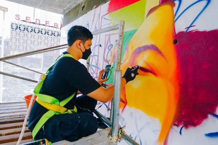 Tampak pemural menggambar mural yang didominasi warna oranye terlihat di bawah jalan layang, di Jalan Prof Dr Satrio, Kuningan, Jakarta Selatan.