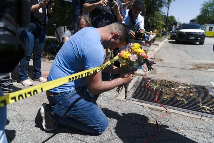 Joseph Avila, kiri, berdoa sambil memegang bunga untuk menghormati para korban yang tewas dalam penembakan Selasa (24/5/2022) di Sekolah Dasar Robb di Uvalde, Texas, Rabu, 25 Mei 2022. 