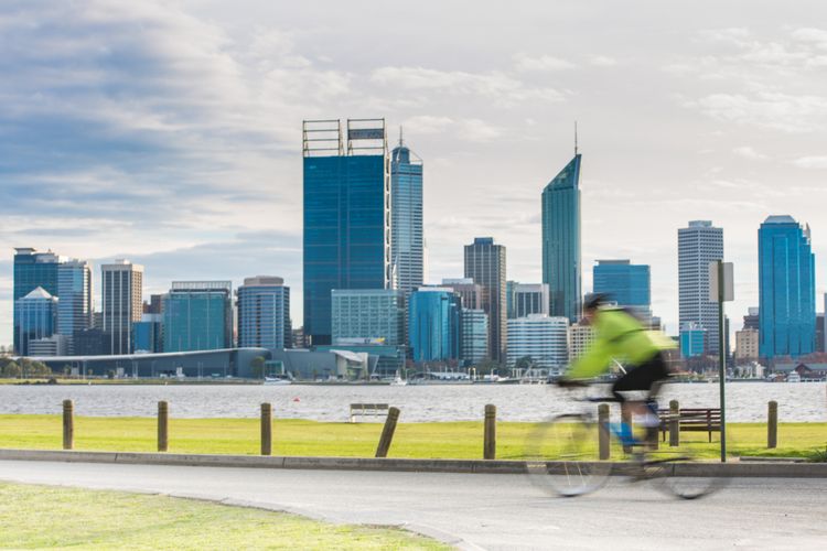 Bersepeda di pinggiran sepanjang Sungai Swan, Perth, Australia Barat, dengan latar kota.