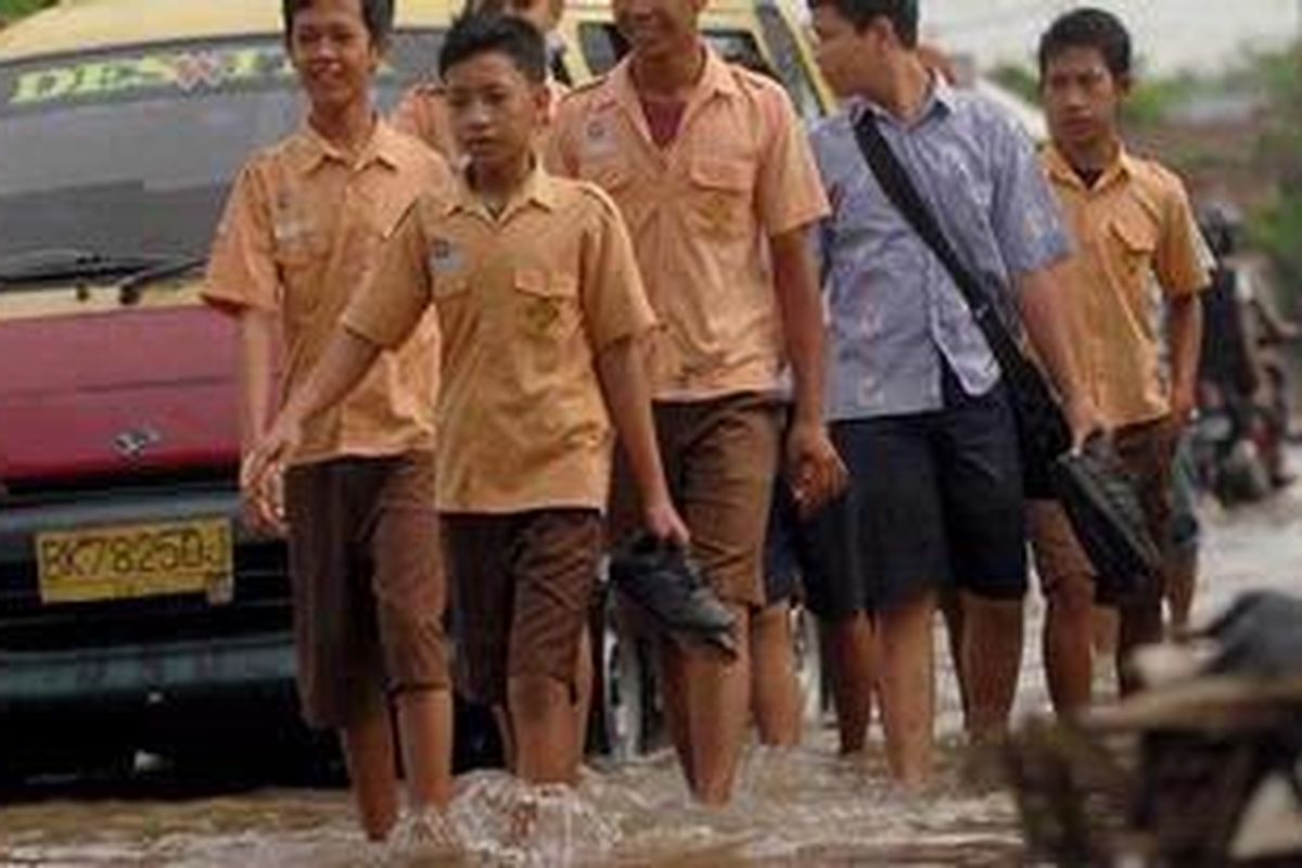Sejumlah siswa pulang karena gedung sekolahnya terandam banjir di Desa Paya Geli, Kecamatan SUnggal, Kabupaten Deli Serdang, Sumut, Jumat (1/4/2011). Selain merendam sebagian besar Kota medan, banjir juga merendam sebagian wilayah perbatasan Kabupaten Deli Serdang.