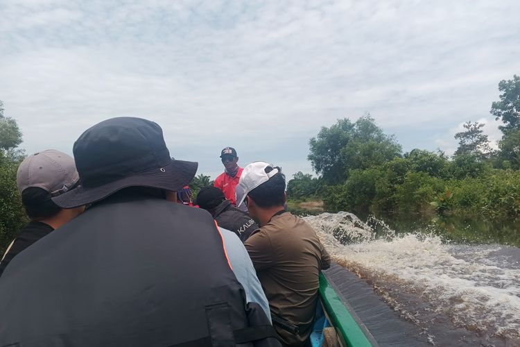 Masturi (baju merah) dan tim dari Kompas.com menyusuri kanal-kanal sempit di tengah perkebunan sawit dengan perahu ketinting di Desa Sungai Besar, Kecamatan Matan Hilir Selatan, Kabupaten Ketapang, pada Senin (27/10/2025).