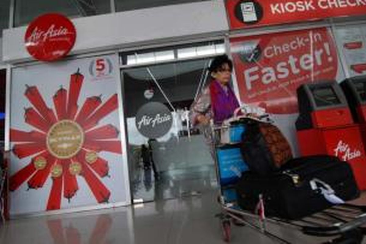 Penumpang melintas di papan iklan AirAsia di Bandara Soekarno-Hatta, Jakarta, 28 Desember 2014. Pesawat AirAsia QZ8501 yang mengangkut 155 penumpang serta 7 awak, hilang kontak pada Minggu pagi, saat penerbangan dari Surabaya menuju Singapura.