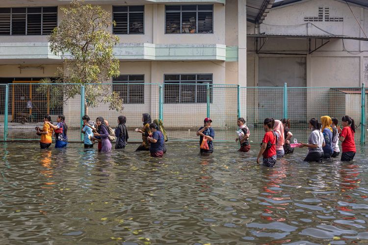 Sejumlah karyawan kawasan industri pelabuhan berjalan menerobos banjir limpasan air laut ke daratan atau rob seusai membersihkan pabrik mereka di kawasan industri Pelabuhan Tanjung Emas Semarang, Jawa Tengah, Jumat (27/5/2022). Karyawan sejumlah pabrik setempat mulai membersihkan sisa-sisa banjir rob di dalam pabrik yang berangsur surut, meskipun air rob masih merendam sejumlah titik akses keluar - masuk kawasan industri pelabuhan dengan ketinggian bervariasi hingga sekitar 70 sentimeter.