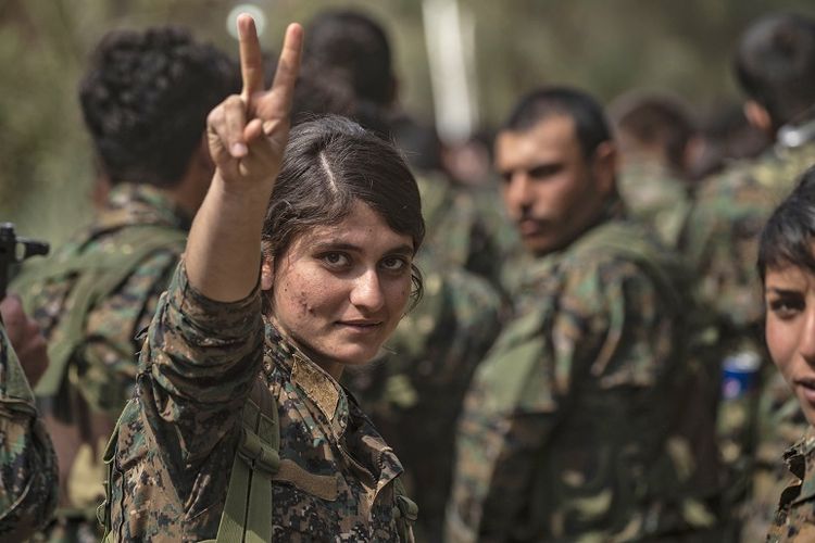 Seorang prajurit perempuan Tentara Demokratik Suriah (SDF) menunjukkan tanda V saat merayakan kemenangan atas ISIS di dekat ladang minyak Omar di provinsi Deir Ezzor, wilayah timur Suriah. 