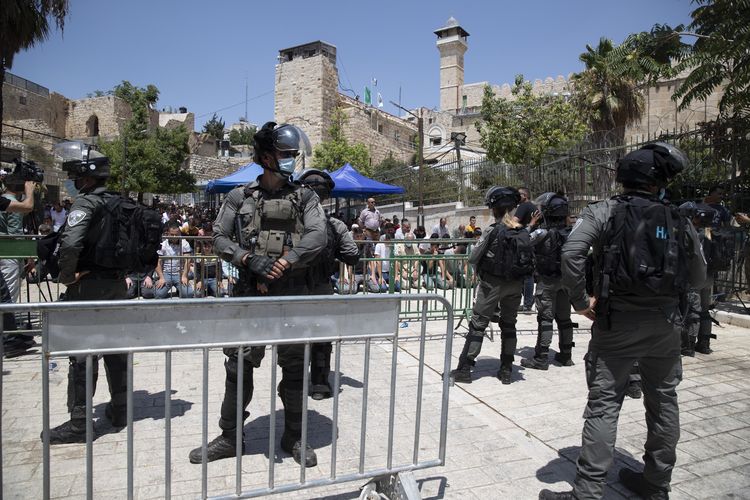 Petugas polisi Israel berjaga-jaga saat warga Palestina shalat Jumat (13/8/2021) di Masjid Ibrahim 
saat memprotes akses konstruksi yang sedang dibangun di sisi Yahudi di Masjid Ibrahimi. [AP Photo/Majdi Mohammed]