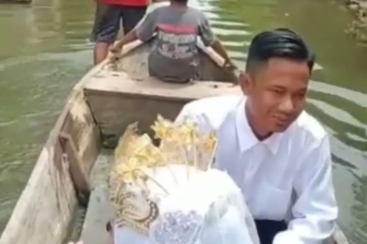 Pasangan Ahmad Hadi Susiwo dan Nurul Izzati, saat dinaikkan perahu lantaran banjir yang menggenang di Dusun Moro, Desa Morocalan, Kecamatan Glagah, Lamongan.